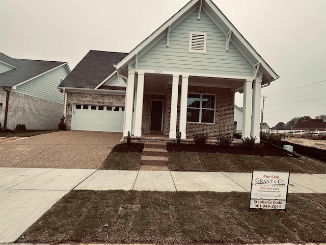 view of front of property featuring a garage, concrete driveway, brick siding, and a shingled roof