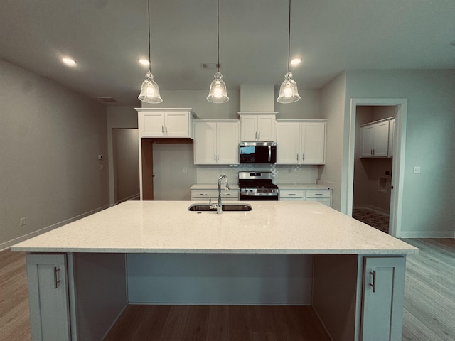 kitchen featuring white cabinets, stainless steel appliances, a sink, and decorative light fixtures