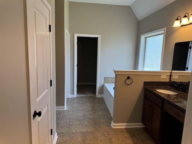 full bathroom featuring vaulted ceiling, a garden tub, vanity, and baseboards