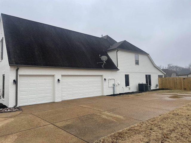 exterior space featuring driveway, brick siding, a shingled roof, and central air condition unit