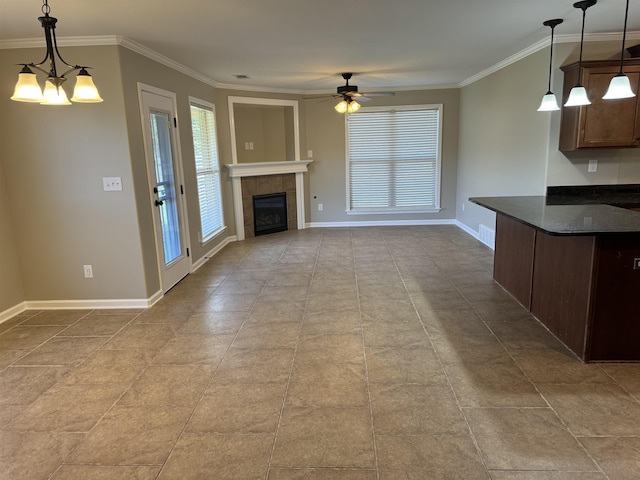 unfurnished living room featuring visible vents, a tiled fireplace, ornamental molding, baseboards, and ceiling fan with notable chandelier