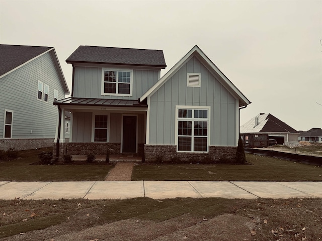 craftsman-style home with metal roof, a standing seam roof, a porch, board and batten siding, and brick siding