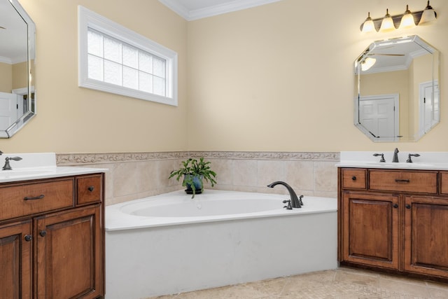 full bath with ornamental molding, two vanities, a garden tub, and a sink