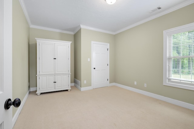 unfurnished bedroom featuring light carpet, ornamental molding, visible vents, and baseboards