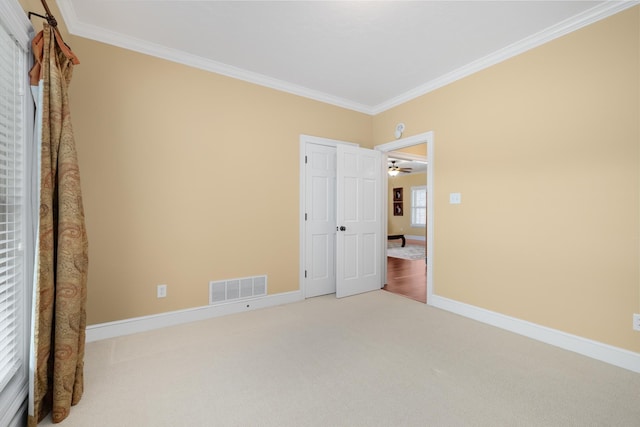 unfurnished bedroom with carpet floors, baseboards, visible vents, and ornamental molding