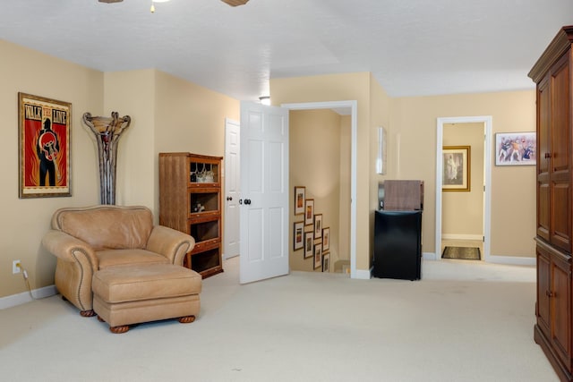 living area featuring baseboards and light colored carpet