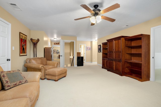 living room featuring a ceiling fan, visible vents, light carpet, and baseboards