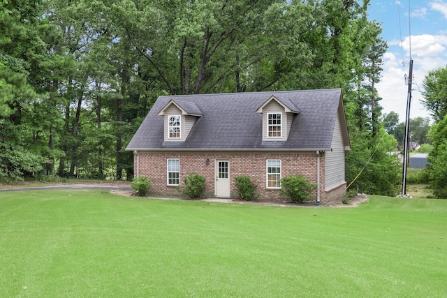 cape cod house featuring a shingled roof, brick siding, and a front lawn