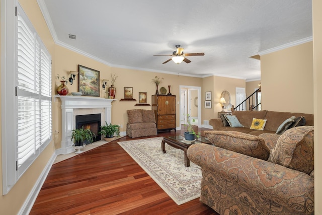 living area featuring visible vents, a fireplace with flush hearth, ornamental molding, dark wood-style flooring, and stairs