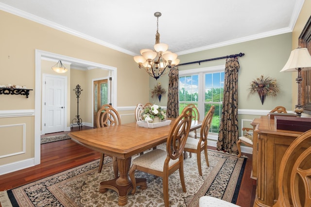 dining room featuring wainscoting, a chandelier, crown molding, and wood finished floors