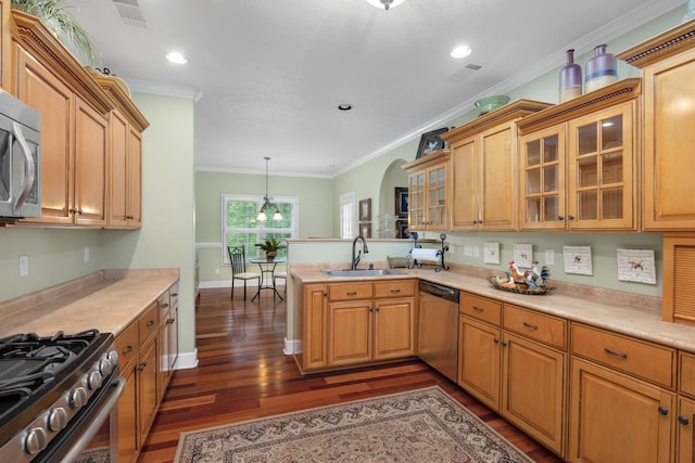 kitchen featuring stainless steel appliances, a peninsula, a sink, visible vents, and crown molding