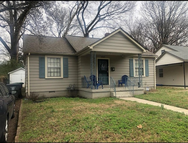 bungalow-style home featuring a front lawn, an outdoor structure, and covered porch