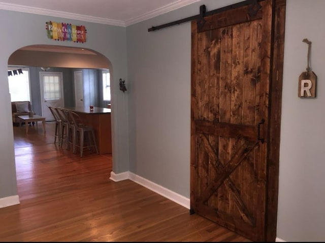 corridor with a barn door, crown molding, and hardwood / wood-style flooring