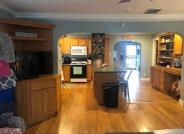 kitchen featuring a center island, a kitchen bar, crown molding, light wood-type flooring, and white appliances