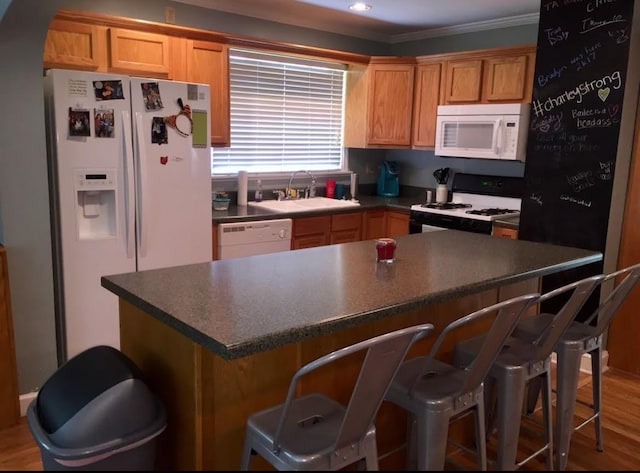 kitchen with sink, white appliances, crown molding, and hardwood / wood-style floors