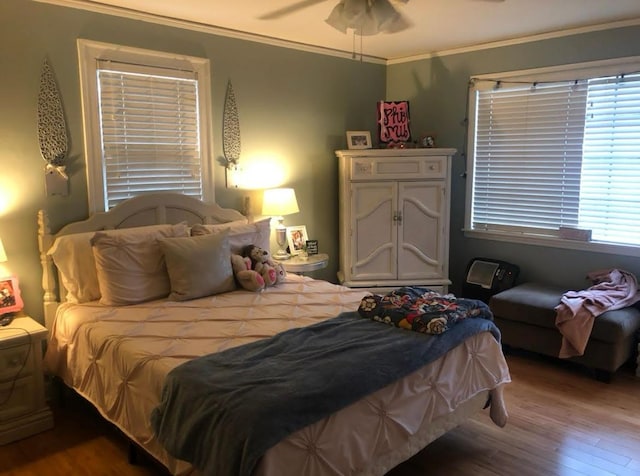 bedroom with ceiling fan, crown molding, and wood-type flooring