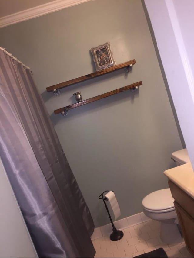 bathroom featuring tile patterned flooring, toilet, ornamental molding, and vanity