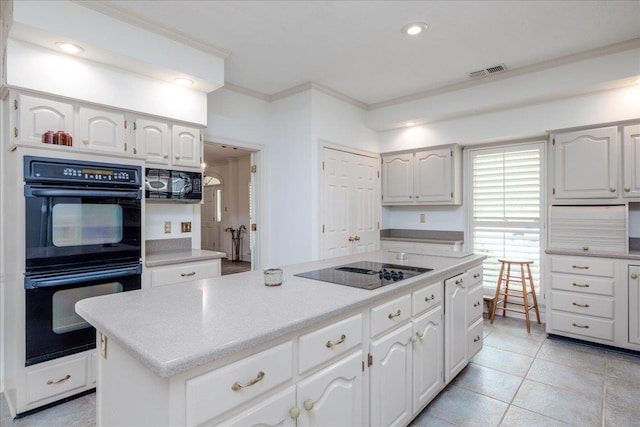 kitchen with light tile patterned floors, white cabinetry, a kitchen island, and black appliances