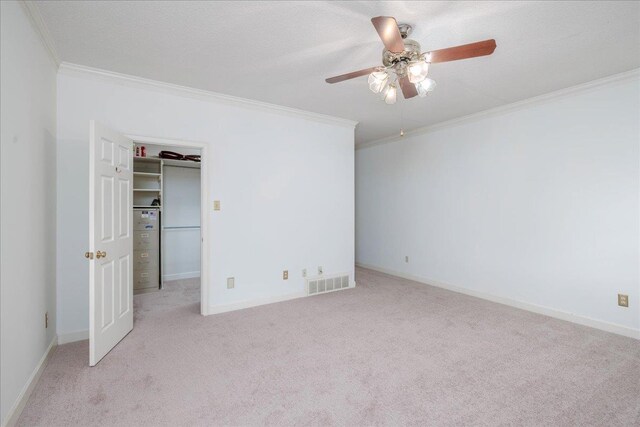 unfurnished bedroom featuring ceiling fan, a closet, crown molding, and light colored carpet