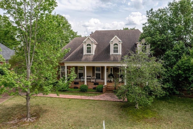 cape cod-style house featuring a front yard and covered porch