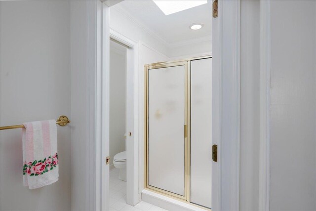 bathroom featuring tile patterned flooring, a shower with door, crown molding, and toilet