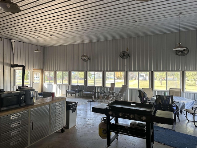 miscellaneous room featuring concrete flooring, a sunroom, and metal wall