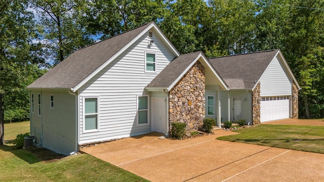 view of front of house featuring a garage, a front lawn, and cooling unit