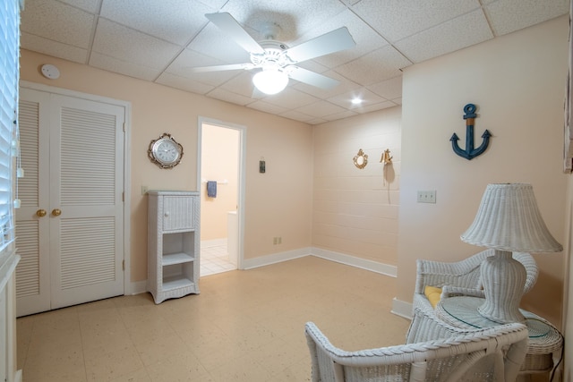 sitting room featuring a drop ceiling, ceiling fan, and light tile patterned floors