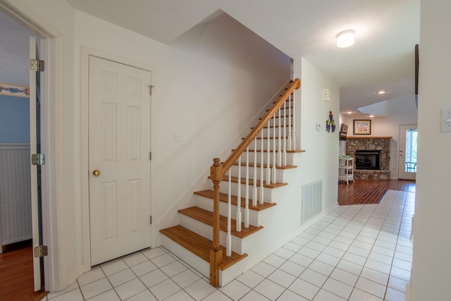 stairs with wood-type flooring and a fireplace