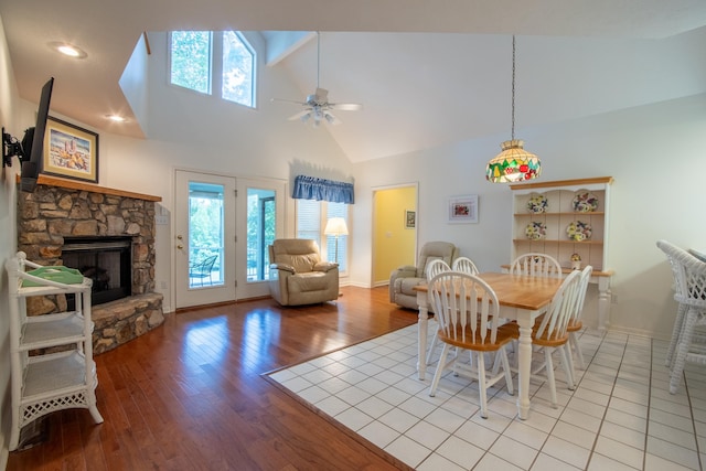 dining area with ceiling fan, high vaulted ceiling, light wood-type flooring, and a fireplace