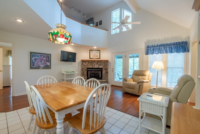 tiled dining area with ceiling fan, high vaulted ceiling, beam ceiling, track lighting, and a fireplace