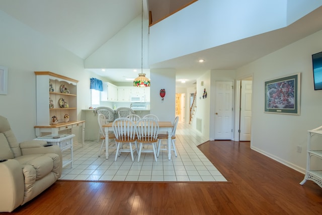 dining room featuring high vaulted ceiling and light tile patterned floors