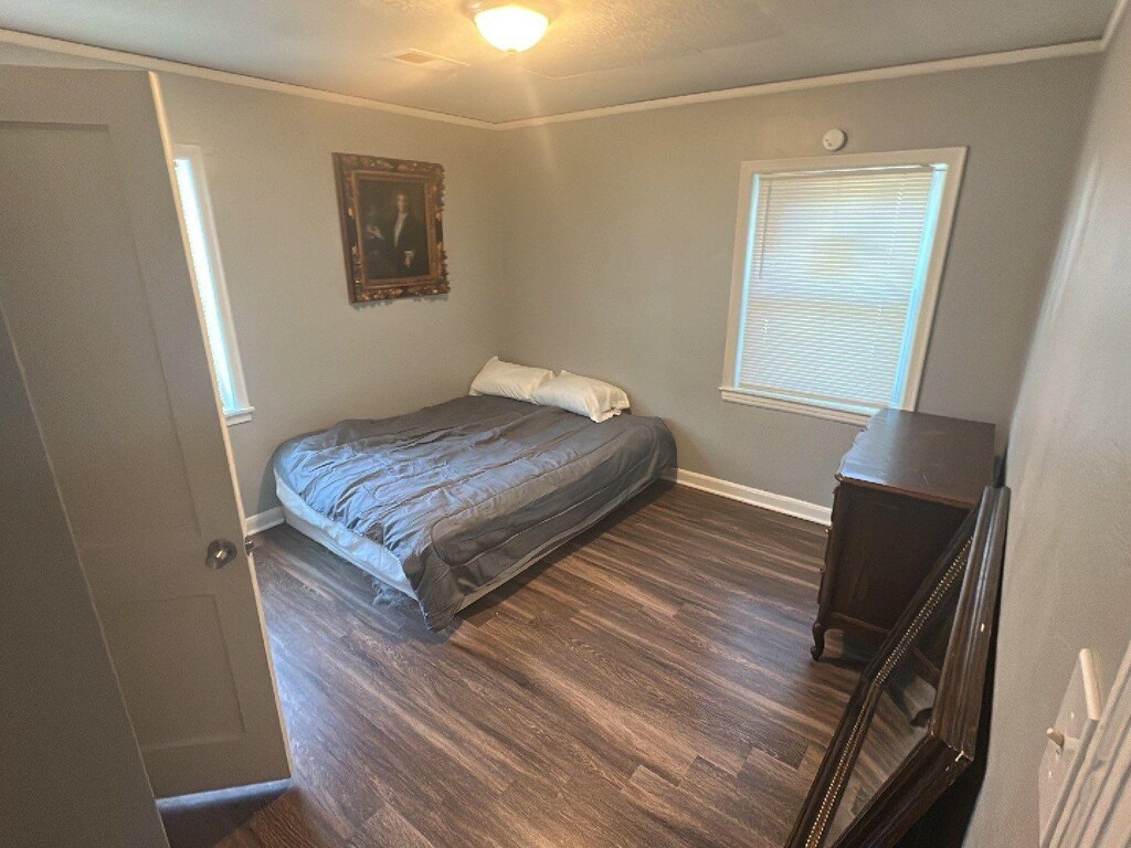 bedroom featuring crown molding and dark wood-type flooring