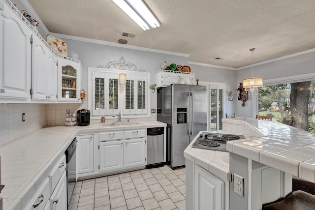 kitchen featuring appliances with stainless steel finishes, tasteful backsplash, pendant lighting, light tile patterned floors, and tile counters