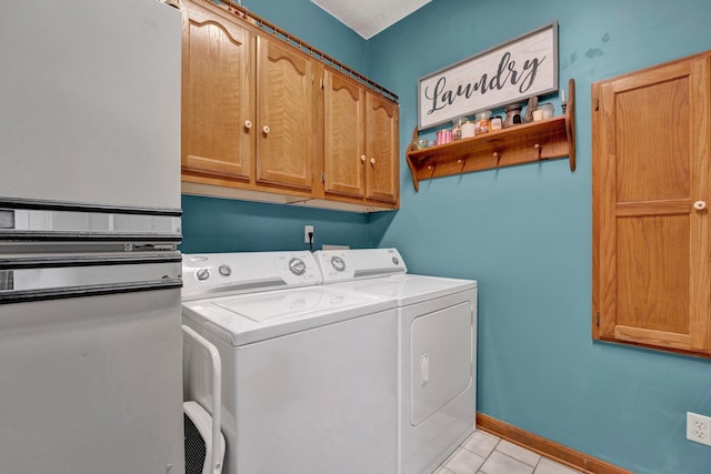 washroom with light tile patterned flooring, washer and clothes dryer, and cabinets