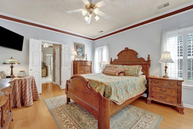 bedroom featuring a textured ceiling, ceiling fan, ornamental molding, and light wood-type flooring