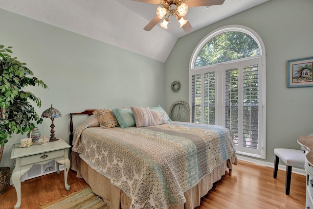 bedroom featuring a textured ceiling, ceiling fan, light wood-type flooring, and lofted ceiling