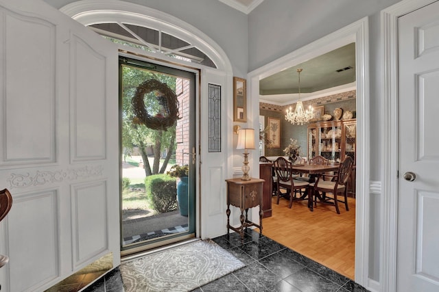 entrance foyer featuring a notable chandelier, ornamental molding, and wood-type flooring