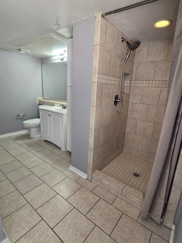 bathroom with toilet, tile patterned floors, tiled shower, and vanity