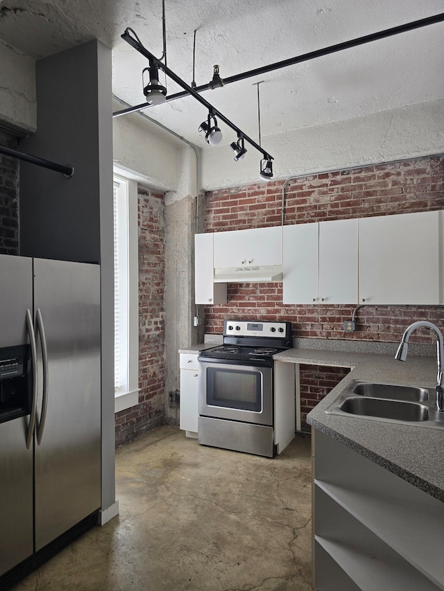 kitchen with stainless steel appliances, white cabinets, a sink, brick wall, and under cabinet range hood