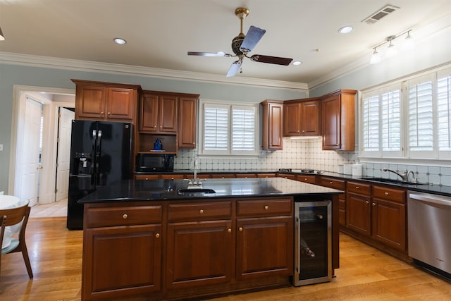 kitchen featuring light hardwood / wood-style floors, wine cooler, black appliances, and a healthy amount of sunlight