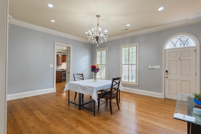 dining room with light wood-type flooring, crown molding, and an inviting chandelier