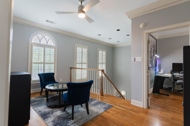 sitting room with ceiling fan, crown molding, and wood-type flooring