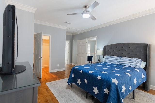 bedroom with ornamental molding, wood-type flooring, a spacious closet, a closet, and ceiling fan