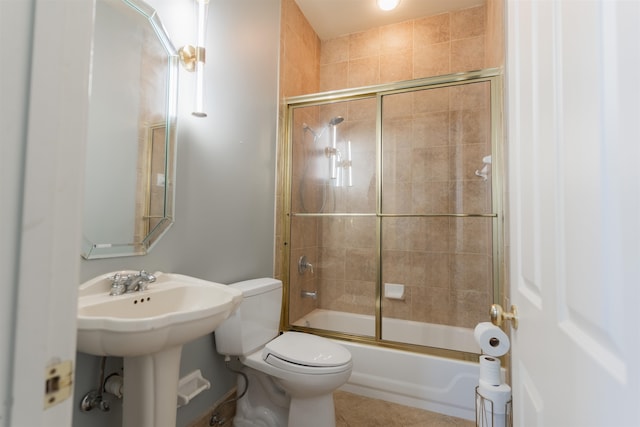 full bathroom featuring tile patterned flooring, toilet, bath / shower combo with glass door, and sink