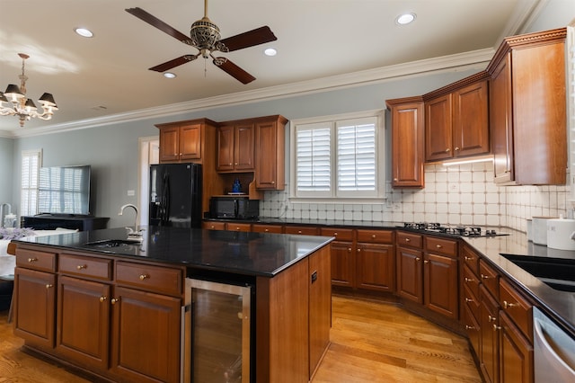 kitchen with plenty of natural light, light hardwood / wood-style flooring, black appliances, and beverage cooler