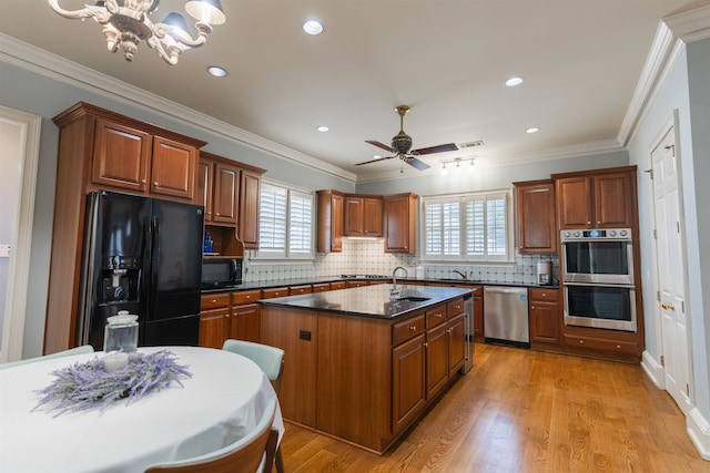 kitchen featuring a wealth of natural light, black appliances, a center island, and light hardwood / wood-style floors