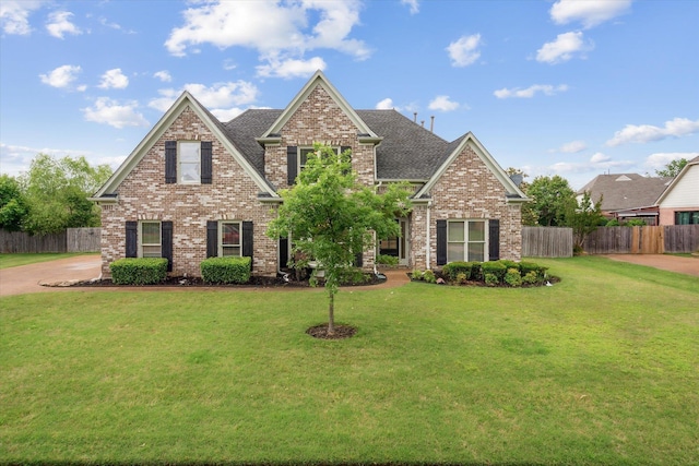 craftsman inspired home featuring brick siding, a front yard, fence, and a shingled roof