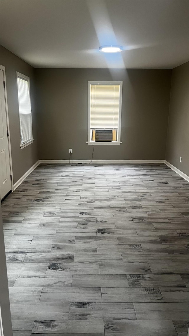 spare room featuring baseboards, cooling unit, and wood finished floors