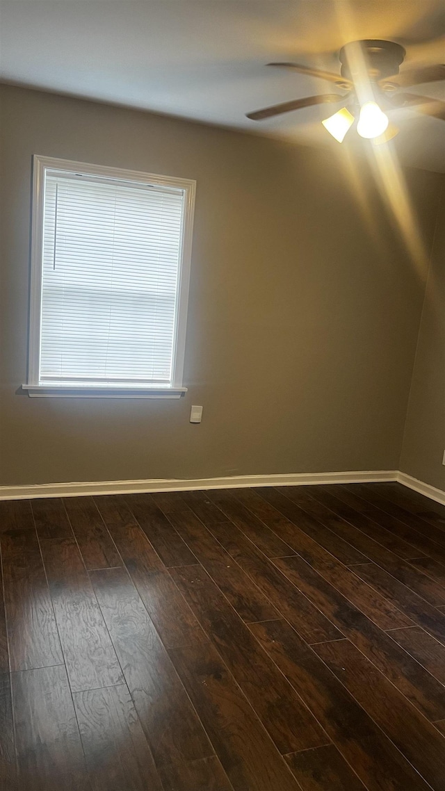 unfurnished room with baseboards, dark wood-style floors, and ceiling fan